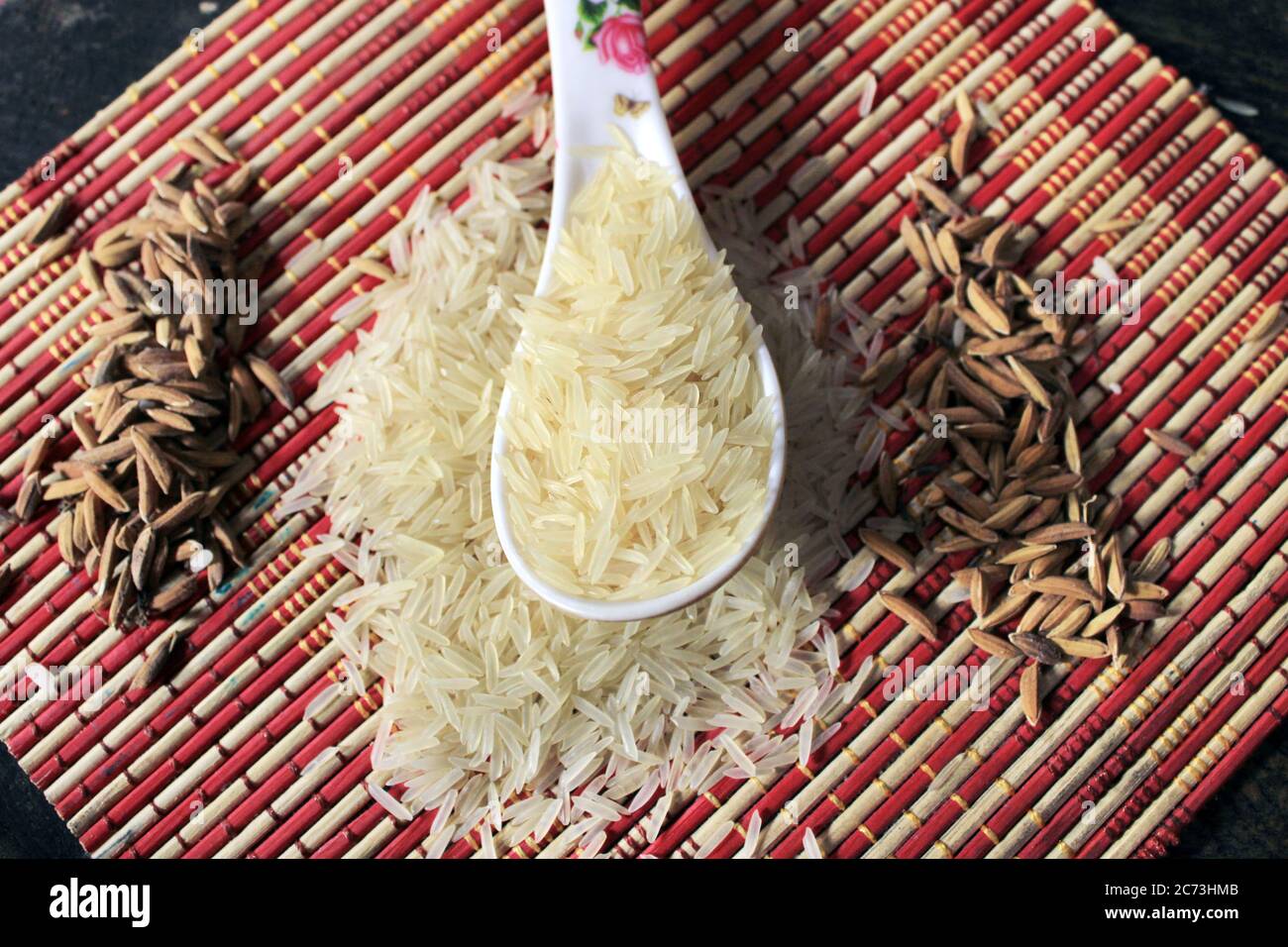 Grains de riz dans une cuillère en plastique blanc sur fond multicolore. Arrière-plan macro de riz blanc. Riz Basmati sur un tas isolé sur fond de motif. Banque D'Images