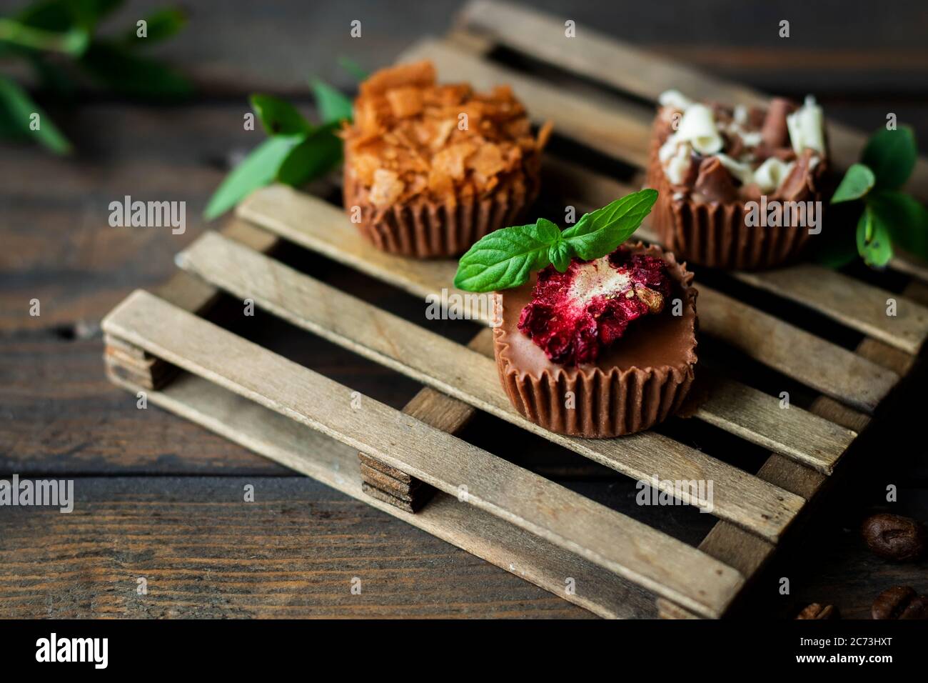 Bonbons au chocolat faits maison avec diverses garnitures. Arrière-plan en bois sombre. Banque D'Images