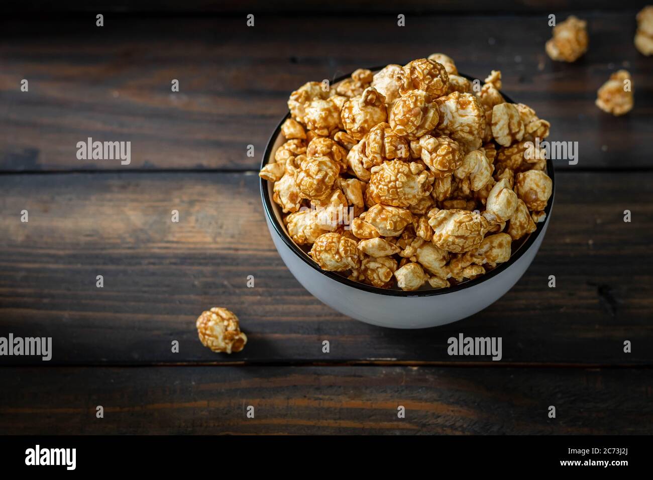 Pop-corn au caramel salé dans une assiette blanche. Arrière-plan en bois sombre Banque D'Images