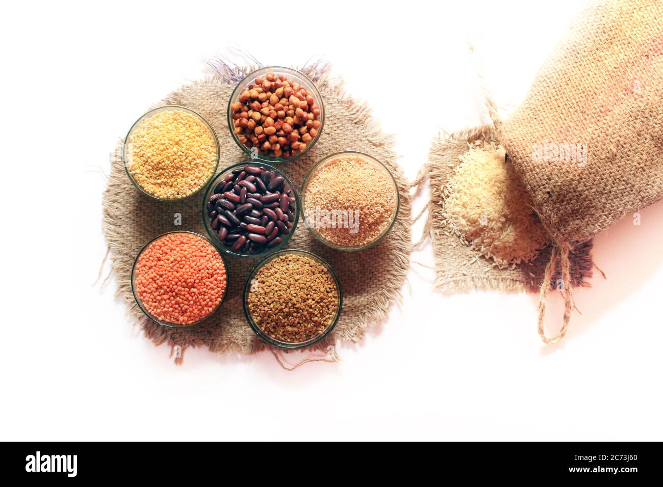 Riz sorti du petit sac isolé sur fond blanc. Différentes impulsions colorées dans les bols. Pois chiches, rein rouge, Lentil, graine de fenugrec, Dalia de blé, Banque D'Images