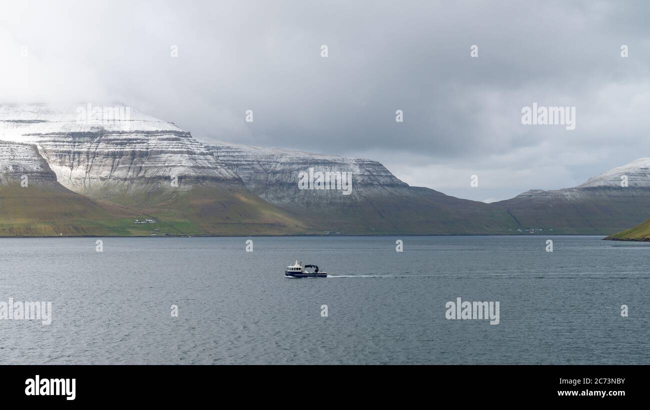 Bateau de pêche naviguant dans un paysage spectaculaire sur les îles Féroé dans l'Atlantique nord Banque D'Images