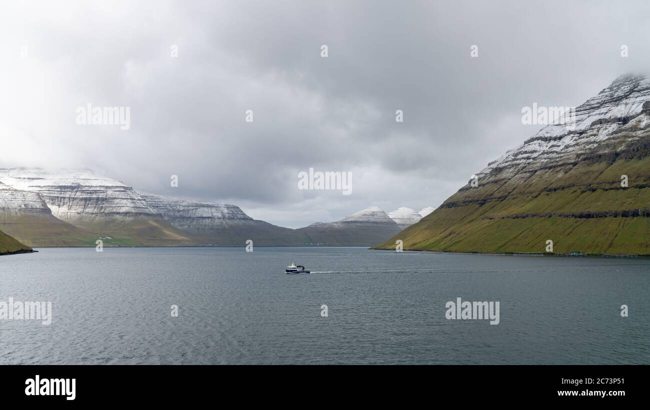 Bateau de pêche naviguant dans un paysage spectaculaire sur les îles Féroé dans l'Atlantique nord Banque D'Images