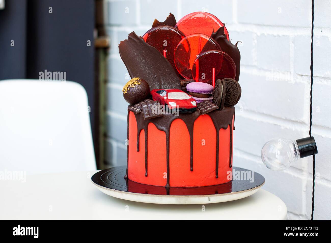 Gateau Rouge Avec Voiture De Course Au Chocolat Decoration Au Chocolat Macarons Sucettes Et Biscuits Fond Blanc Photo Stock Alamy