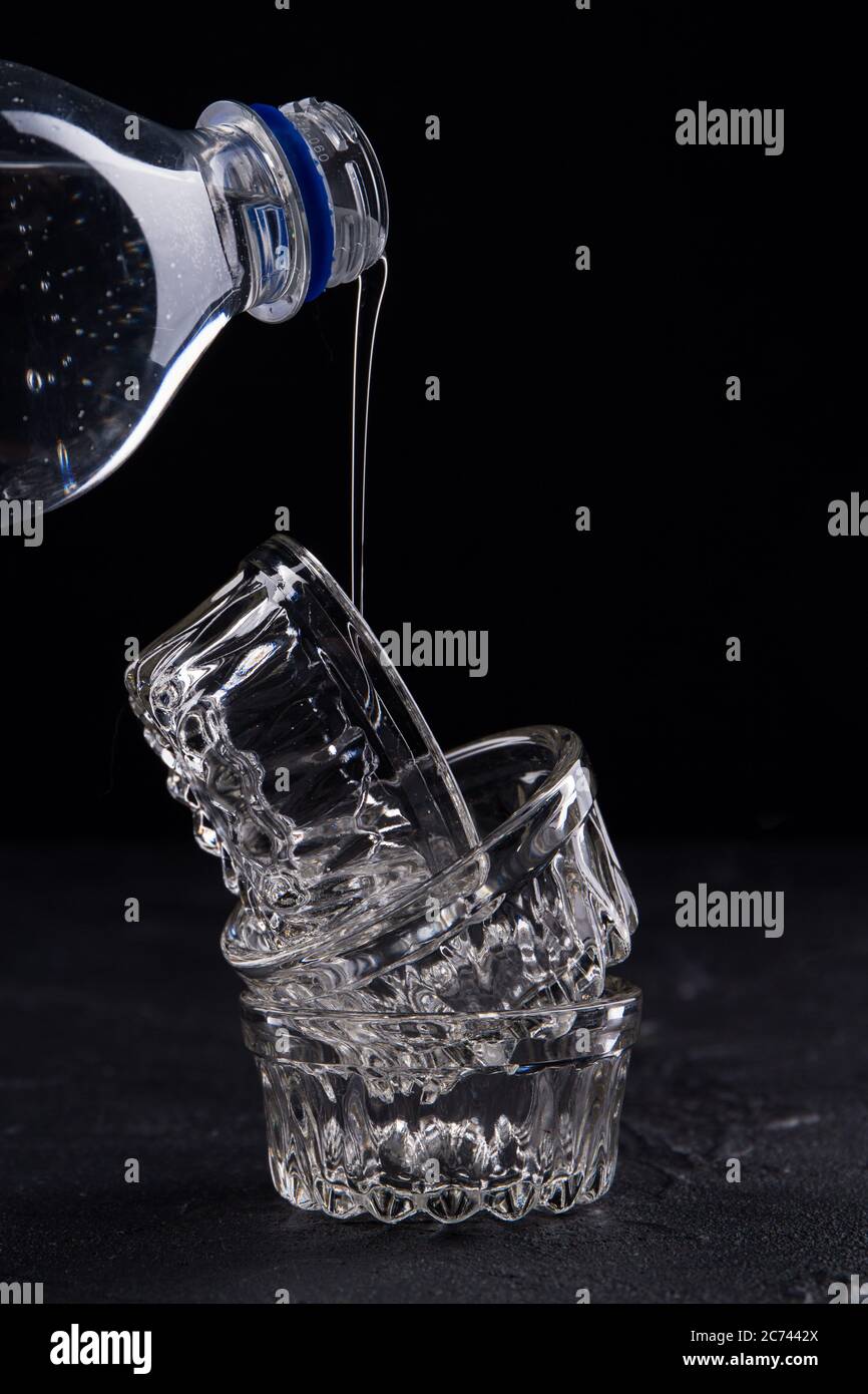 Eau s'injectant dans la bouteille en plastique et les récipients en verre. Banque D'Images