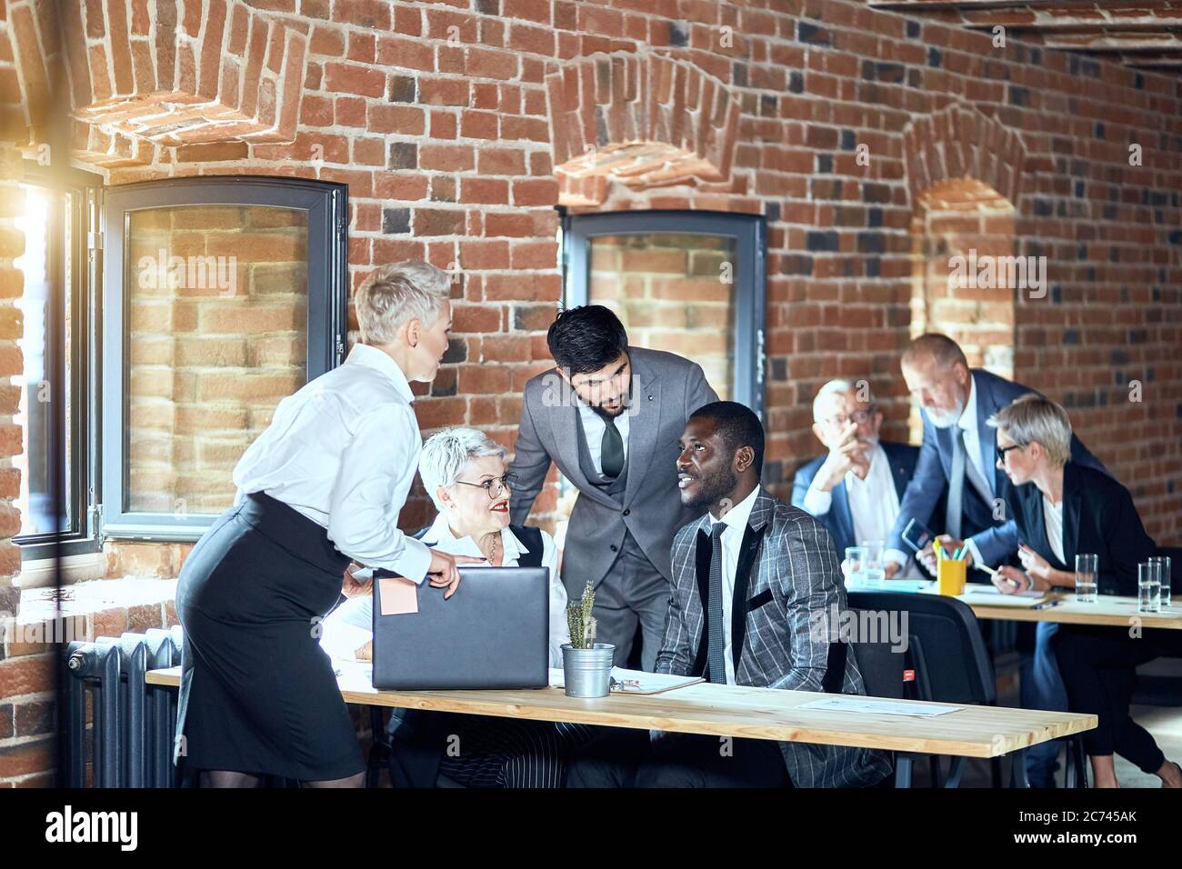 Au premier plan, deux femmes blanches blondes, un homme brunette à barbe caucasienne, un homme africain parle. Sur le fond deux hommes blancs blonds et un wom Banque D'Images