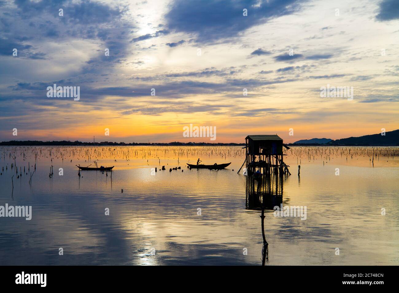 Paysage merveilleux à Lap an Lagoon, Vietnam avec la maison flottante, bateau en bois et ciel coloré étonnant de lever du soleil. Banque D'Images