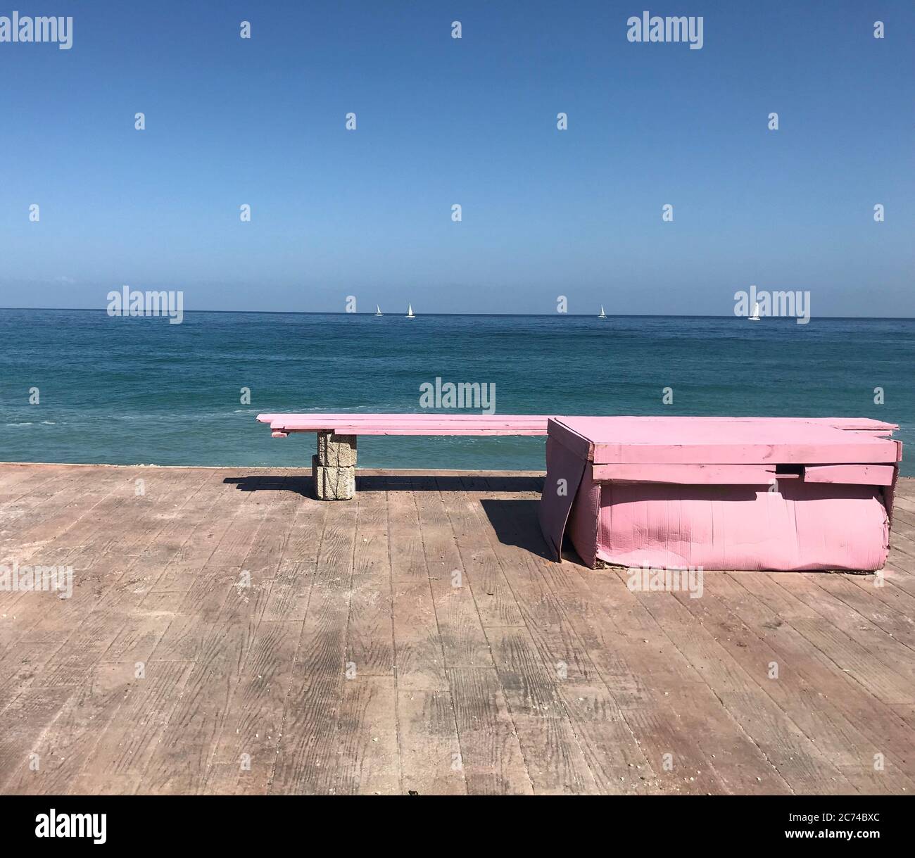 Banc rose sur la plage dans le ciel bleu du matin. Banque D'Images