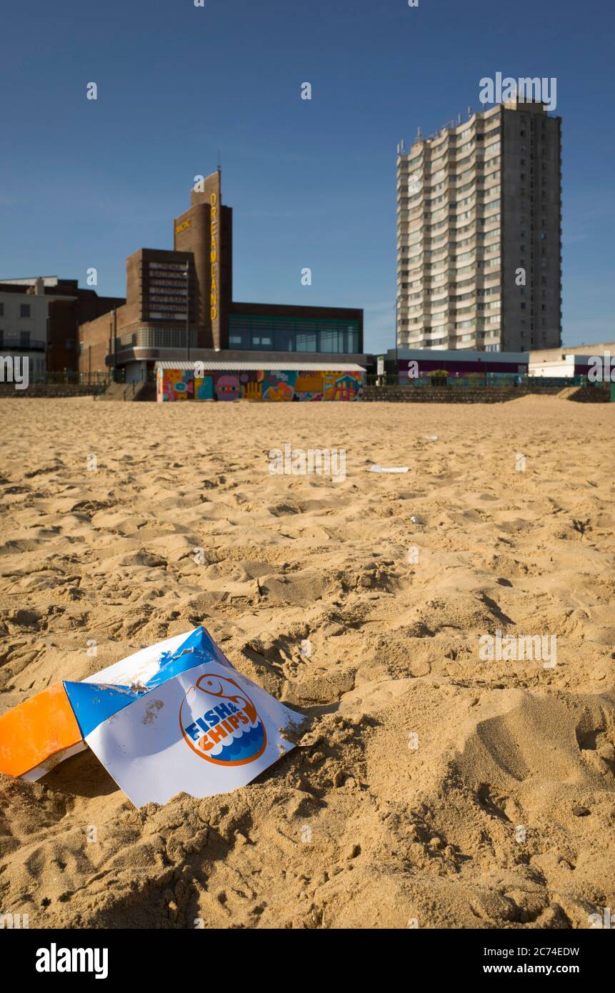 Jeter la boîte vide Fish and chips près de Dreamland sur le sable à la plage de Margate dans le Kent. Banque D'Images