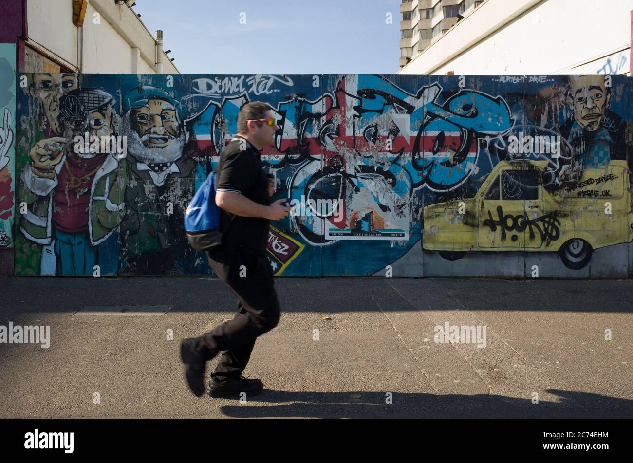 Marche piétonne devant le mur du graffiti à Margate, Kent, Angleterre. Banque D'Images