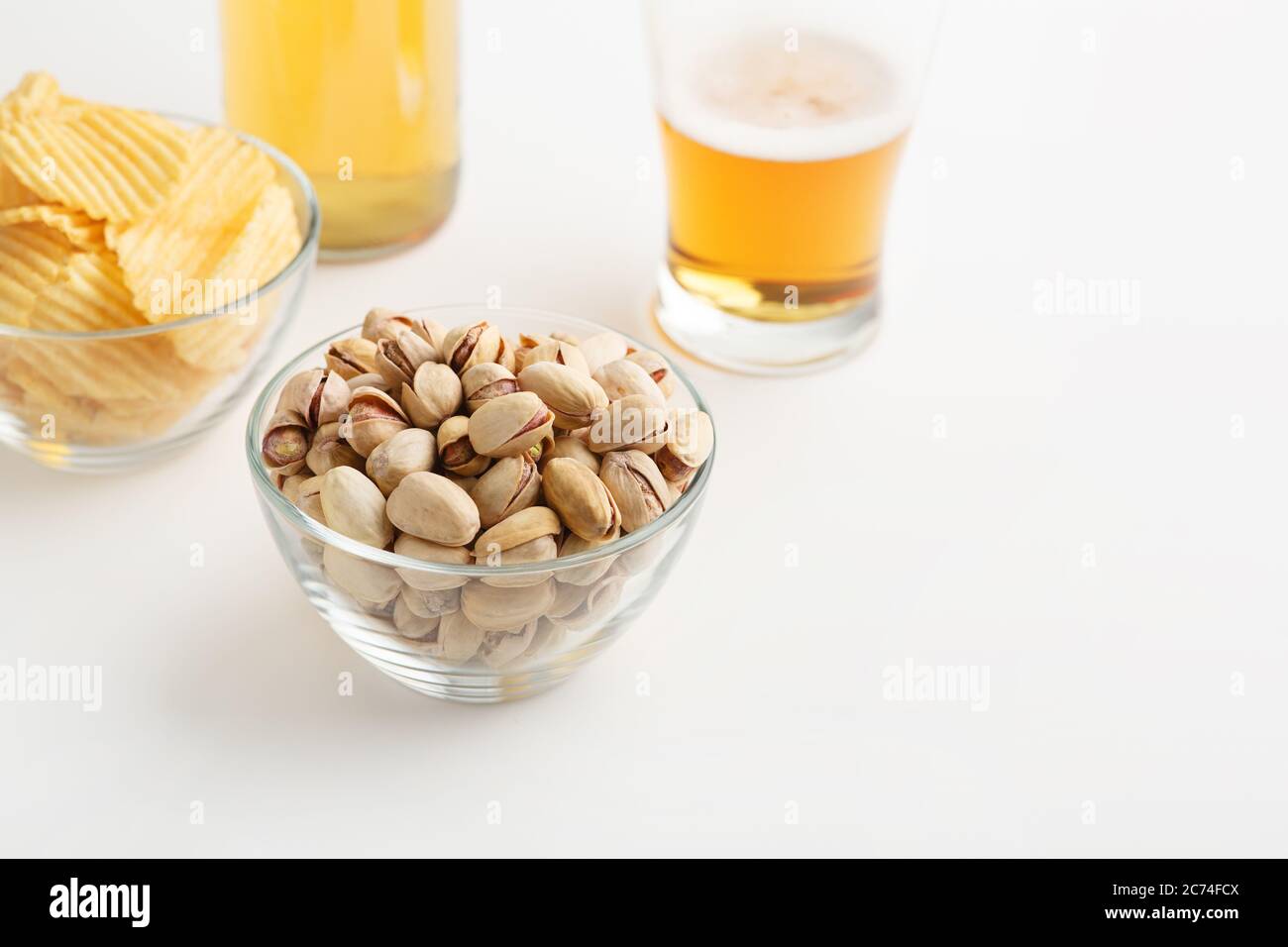 Délicieux repas à la bière. Pistaches et chips dans des assiettes en verre, verre avec bière et bouteille Banque D'Images