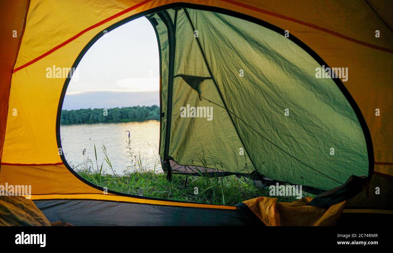 Une tente avec une fenêtre ouverte se dresse sur les rives de la rivière. De la tente ouverte vous pouvez voir la rivière Banque D'Images