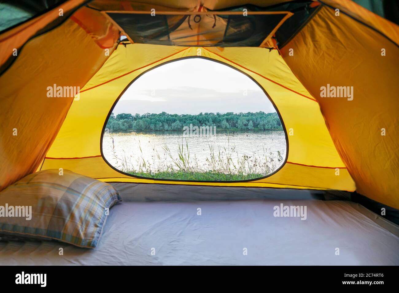 Une tente avec une fenêtre ouverte se dresse sur les rives de la rivière. De la tente ouverte vous pouvez voir la rivière Banque D'Images