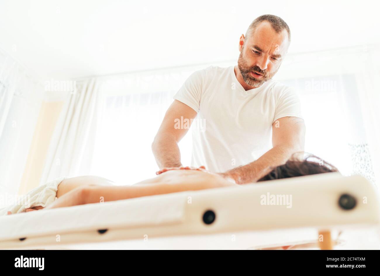 Homme de masseuse faisant des manipulations de massage sur le dos du client et de communiquer avec pacient Banque D'Images