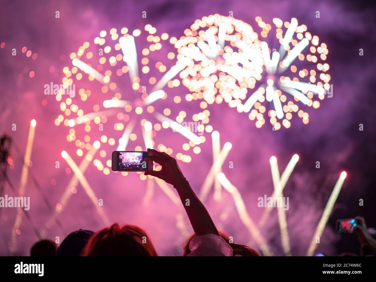 Main levée avec prise de vue horizontale de nuit feux d'artifice ciel smartphone vidéo. Divertissement en arrière-plan coloré et lumineux avec spectacle laser. Banque D'Images