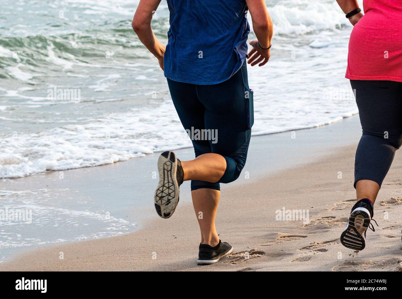 Vue arrière des femmes qui couleurs sur la plage, à côté de l'océan, avec baskets. Banque D'Images