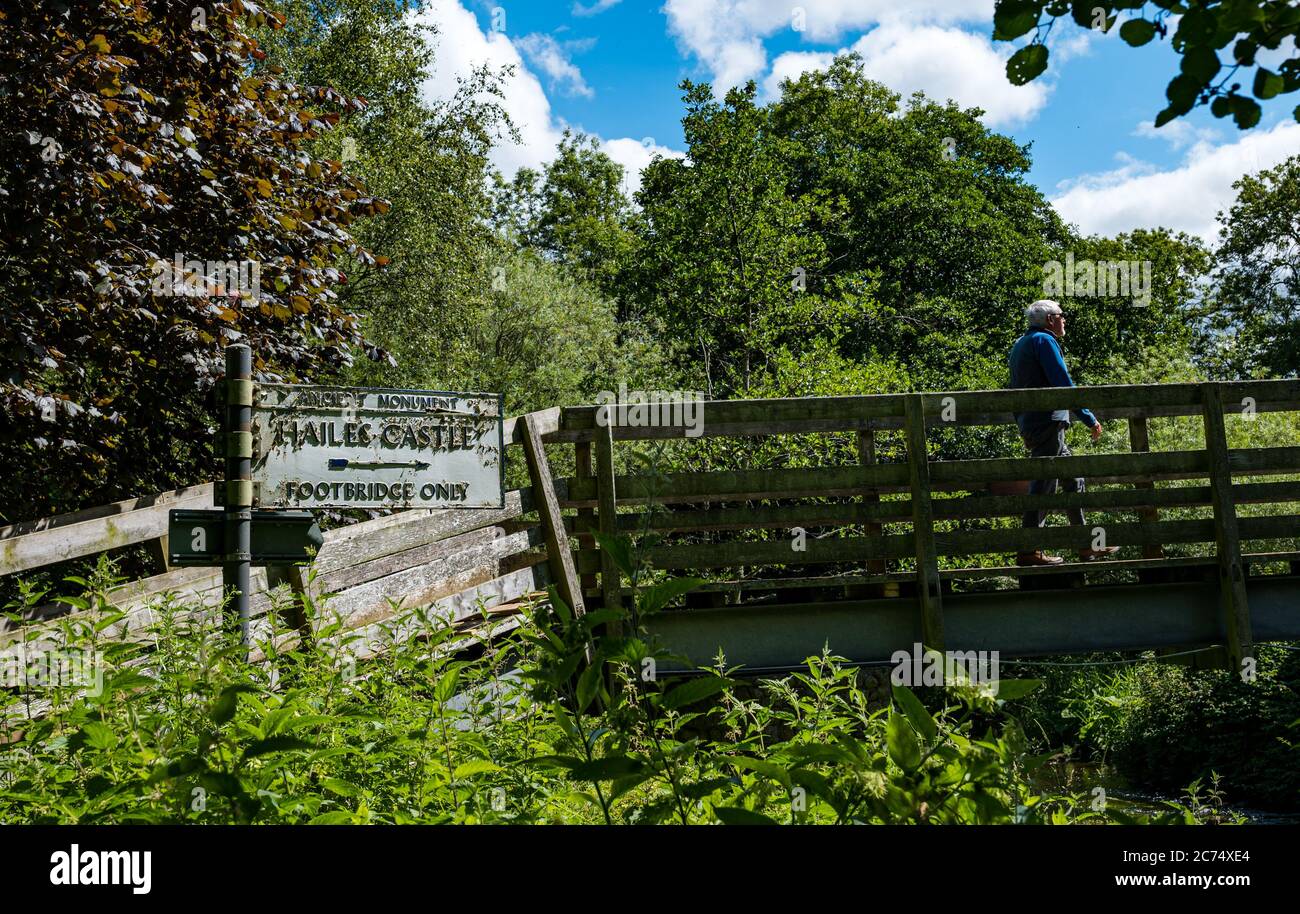 East Lothian, Écosse, Royaume-Uni, 14 juillet 2020. Un homme de haut niveau qui se promit sur une passerelle en bois menant au château de Hailes, un établissement historique d'Environnement Écosse, lors d'une journée d'été ensoleillée avec un ancien panneau indiquant le chemin Banque D'Images