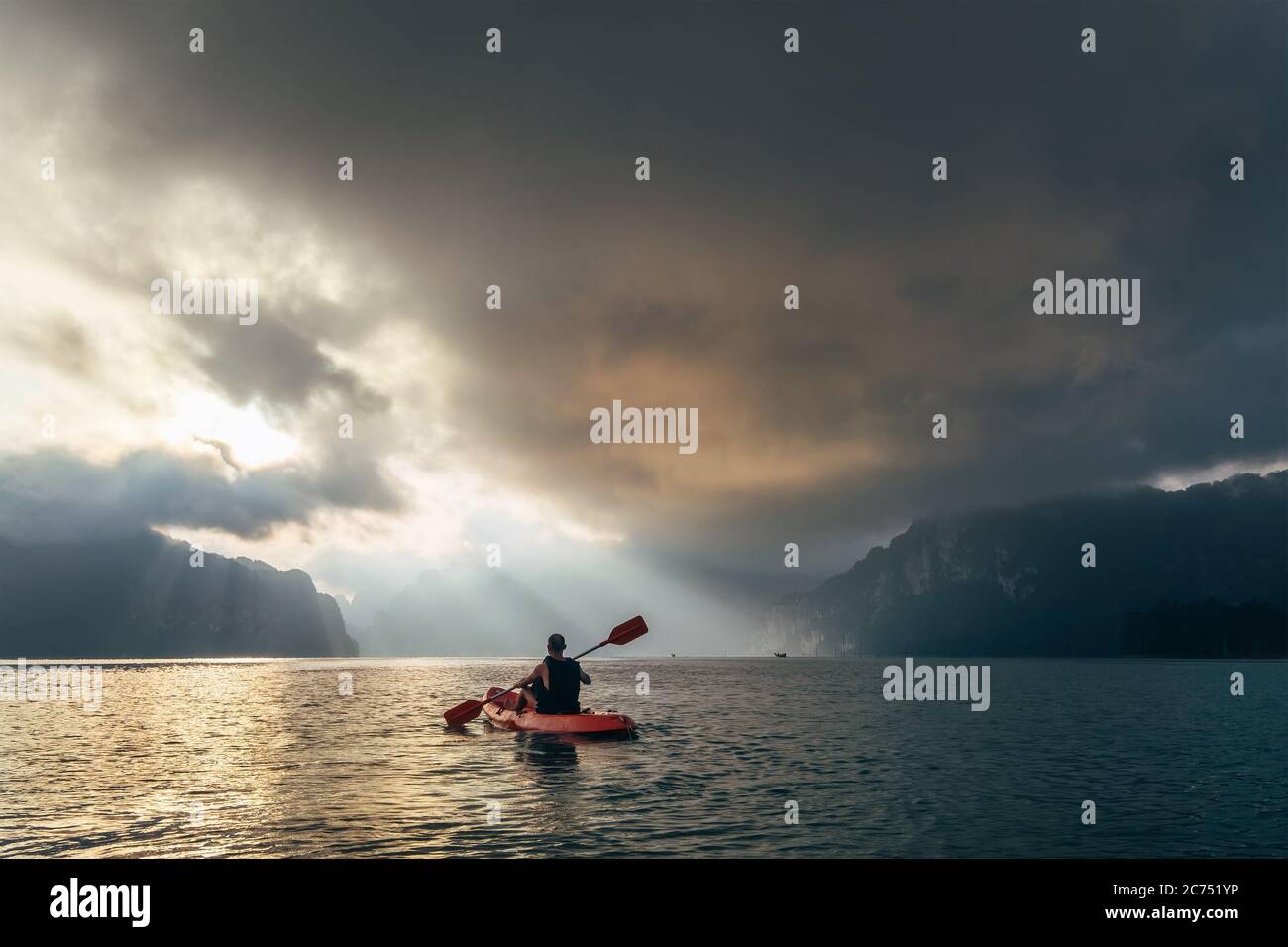 Homme en kayak, en meeting lever du soleil sur le lac Choow LAN, parc national de Khao Sok, Thaïlande Banque D'Images