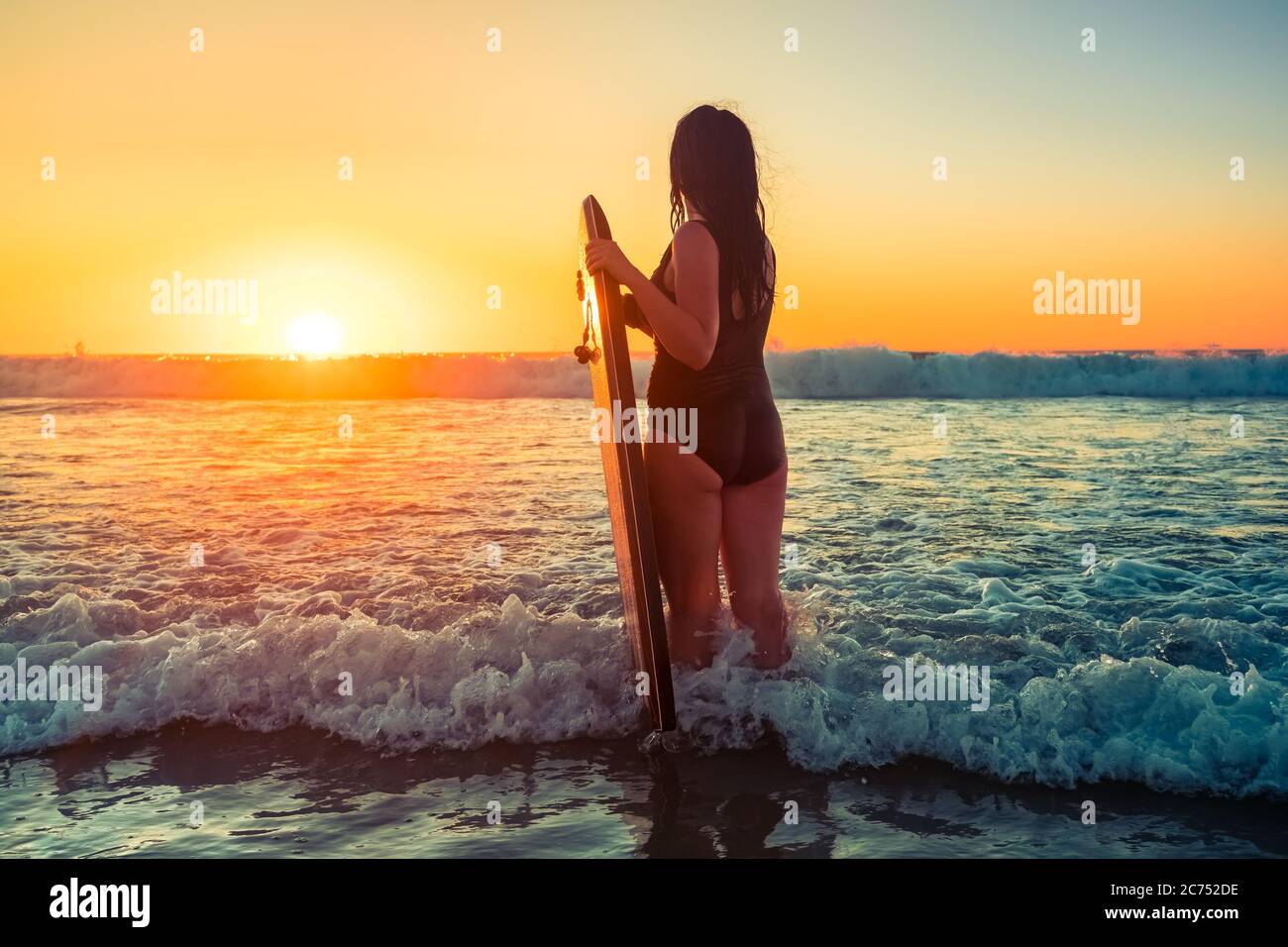 Femme avec bodyboard attrapant des vagues au coucher du soleil, Moana Beach, Australie méridionale Banque D'Images