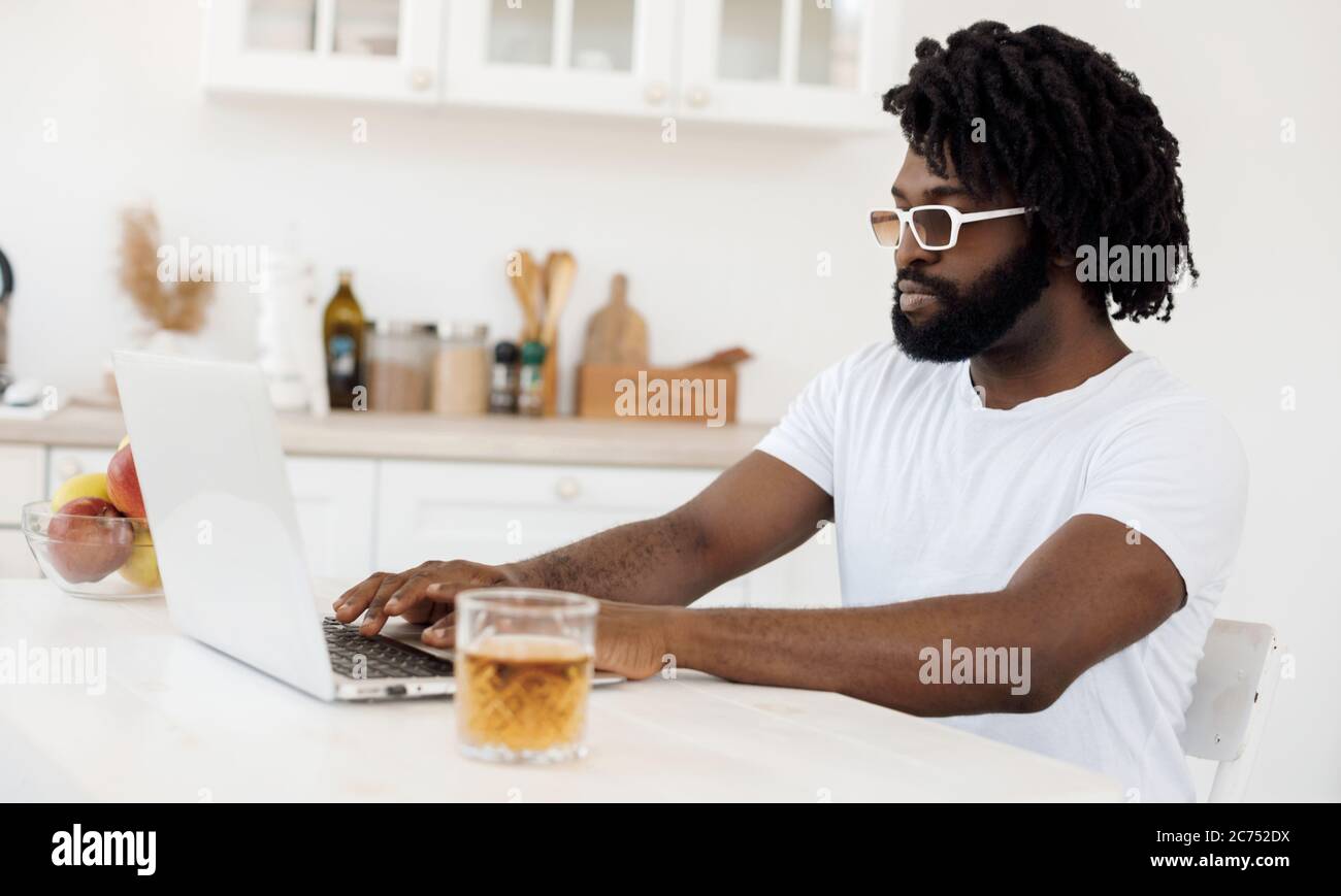 Jeune homme noir travaillant à la maison avec un ordinateur portable Banque D'Images
