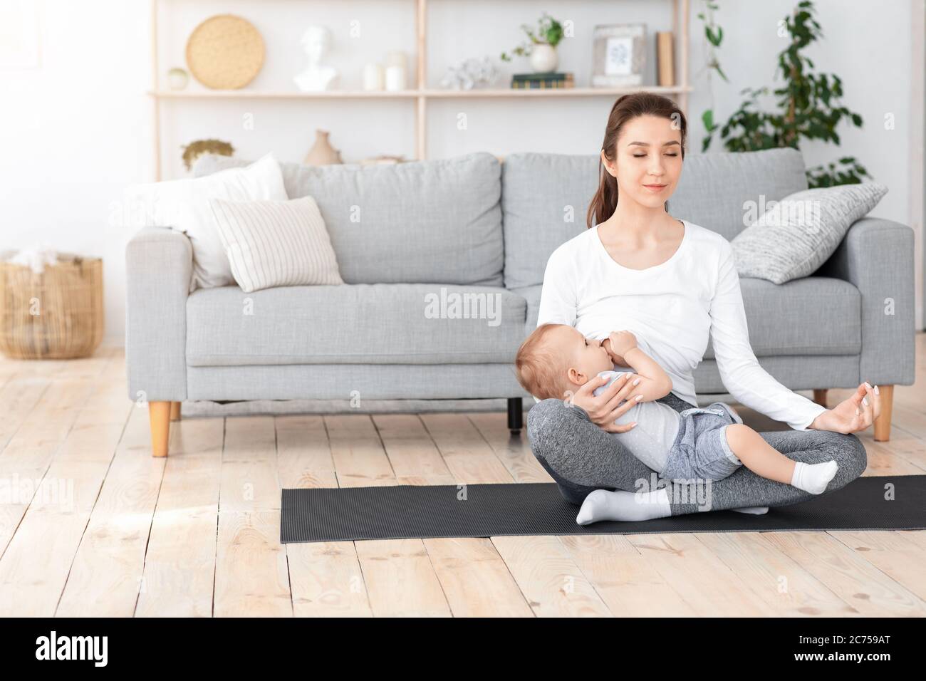 Faire face au stress de maternité. Bébé allaitant et méditant à la maison Banque D'Images