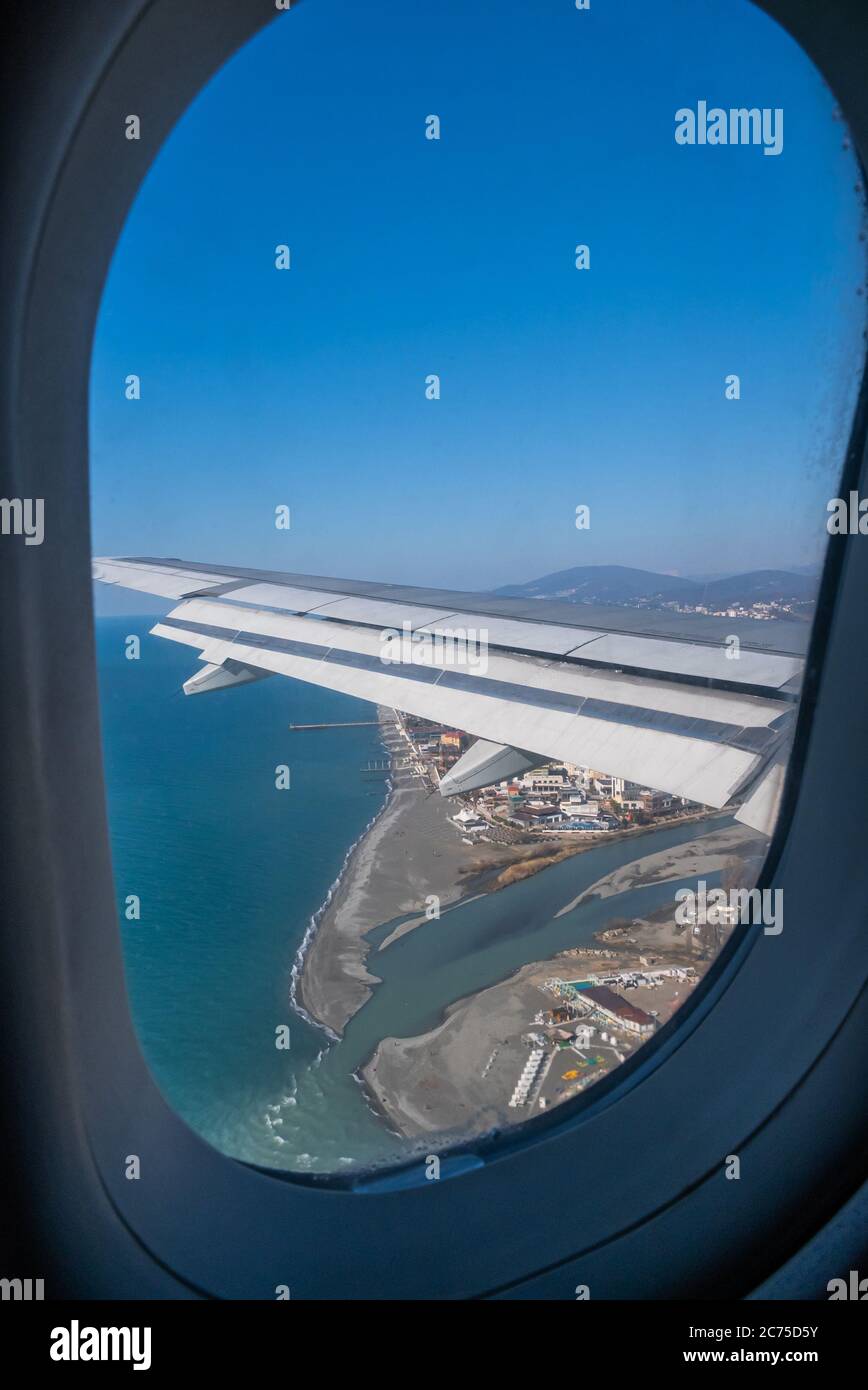 L'aile d'un avion volant au-dessus de la ville, de la mer et de la rivière à travers le hublot en verre. Sotchi, Russie Banque D'Images
