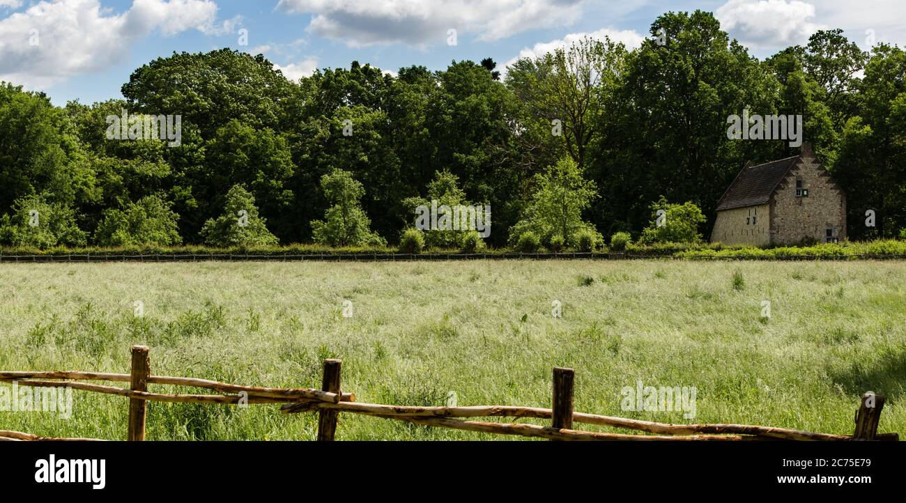 Large panorama de paysage rural flamand de pâturage avec clôture en bois une ancienne maison en brique et une ligne de bois dans le fond quelques nuages blancs Banque D'Images