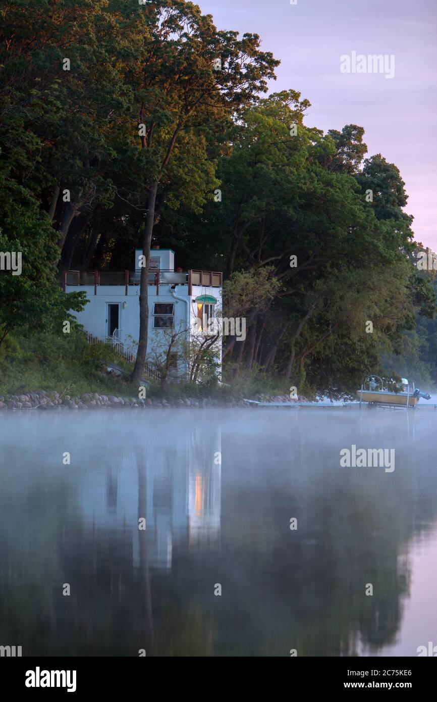 Boathouse réfléchit sur l'eau calme à travers le brouillard du matin Banque D'Images