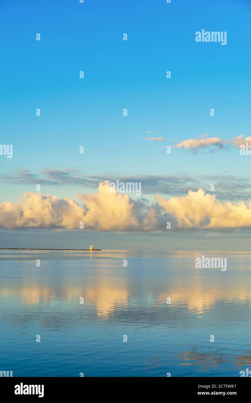 Les nuages dorés du matin se reflètent dans les eaux calmes du port de Summerside, à l'Île-du-Prince-Édouard, au Canada. Phare d'Indian point à l'horizon. Banque D'Images
