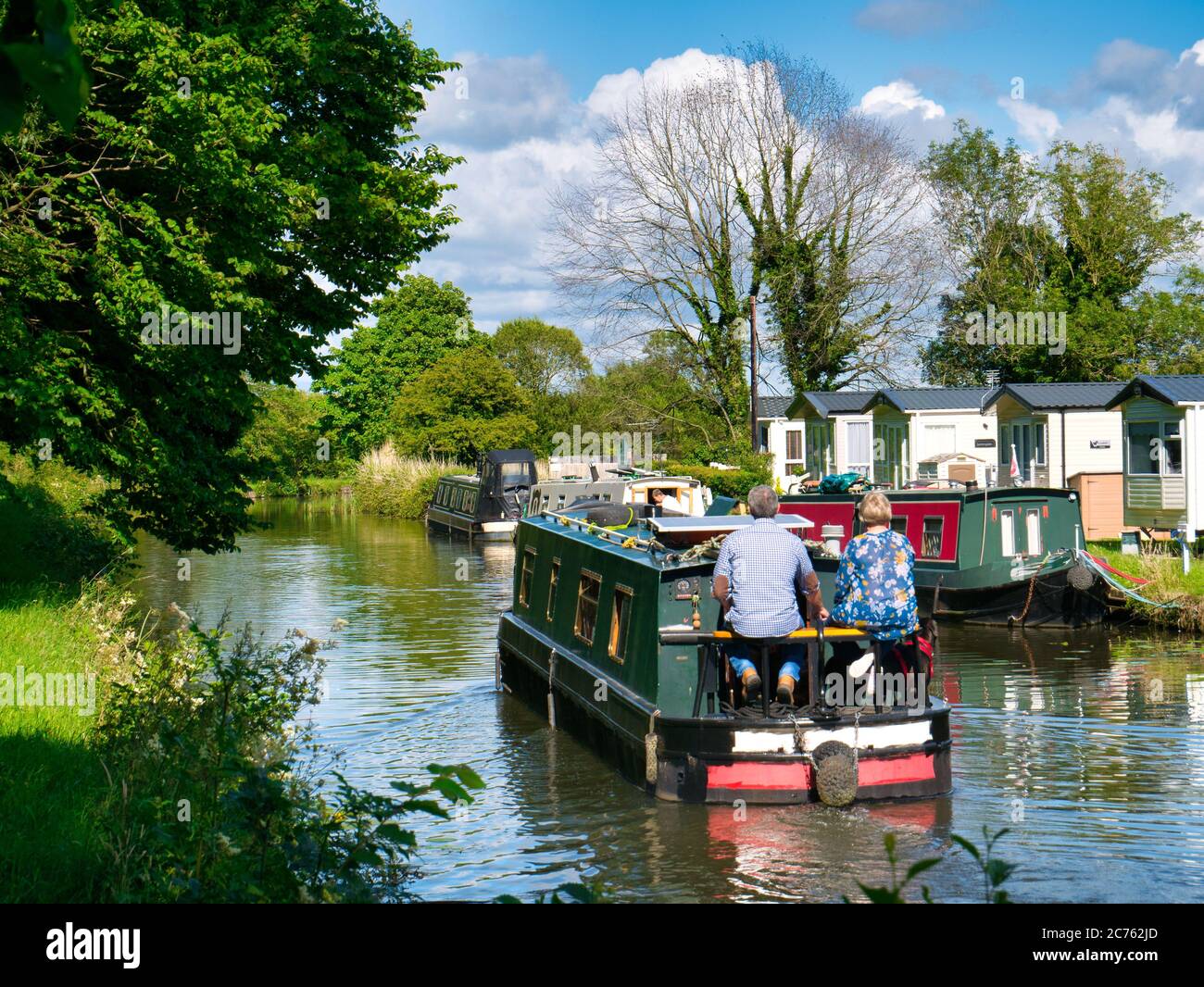 Vacanciers sur un bateau à narrowboat qui navigue sur le canal Leeds-Liverpool dans le Lancashire, paisible et rural. Pris par une journée ensoleillée en été. Banque D'Images