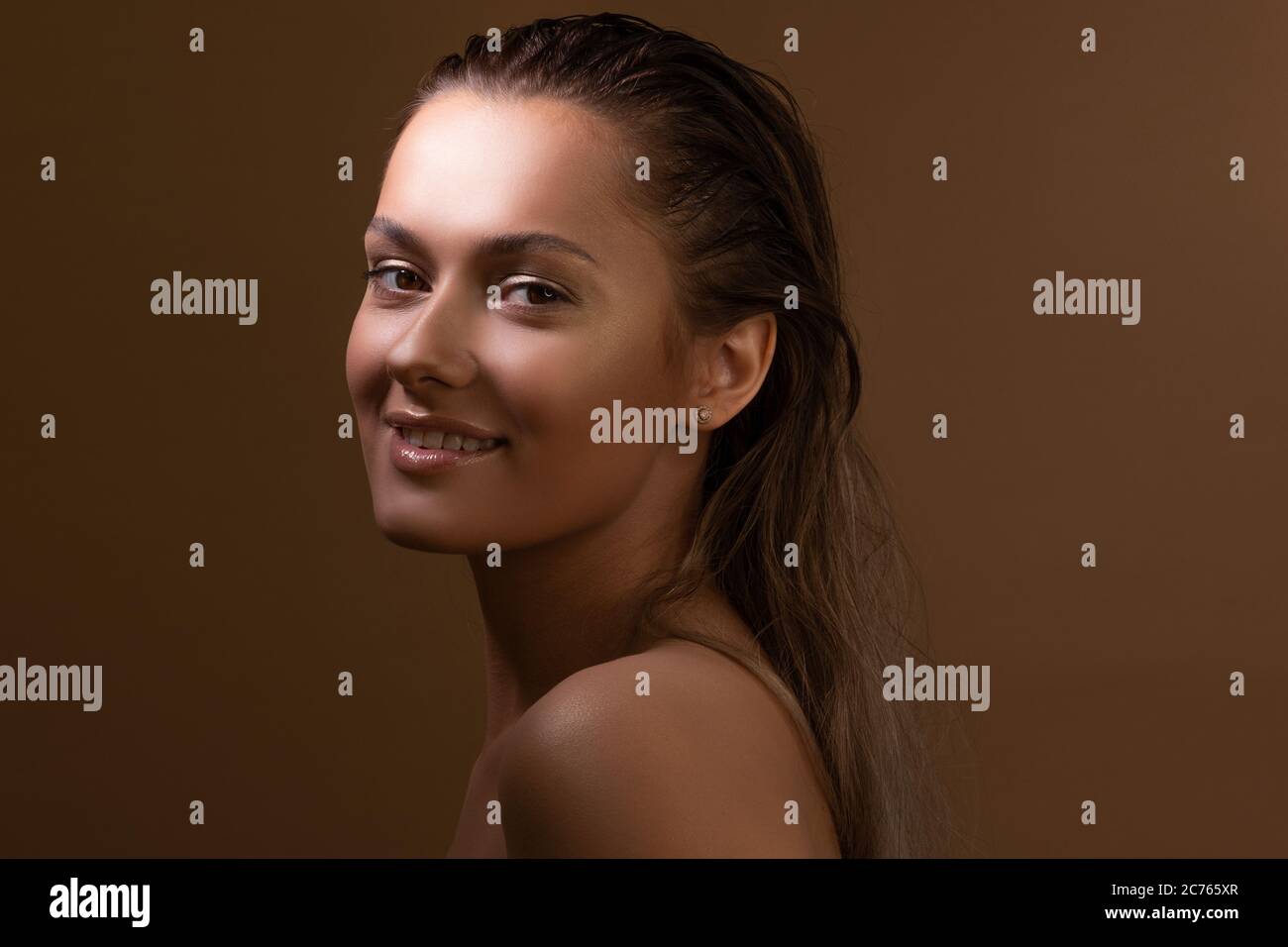 Une petite fille bronzée et douce avec une peau claire et éclatante. Santé et soins de la peau. Portrait d'une charmante brunette avec une peau sombre sur fond beige. Banque D'Images