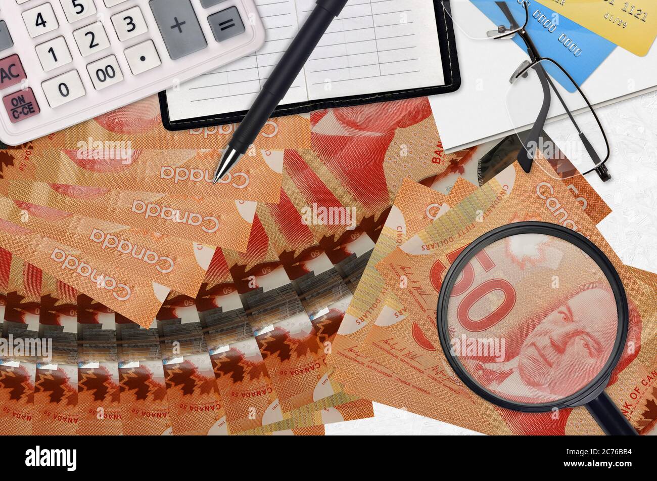 50 billets en dollars canadiens et calculatrice avec lunettes et stylo. Concept de saison de paiement d'impôt ou solutions d'investissement. Recherche d'un emploi avec un salaire élevé ea Banque D'Images