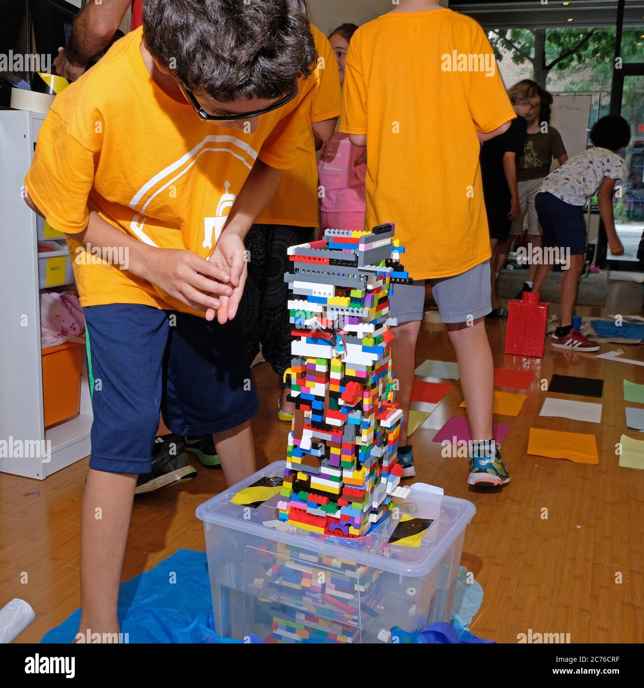 Camp de jour. Brooklyn, NY. UN camp spécialisé dans la technologie et la robotique. Garçon travaillant avec des blocs lego pour construire une tour. Banque D'Images