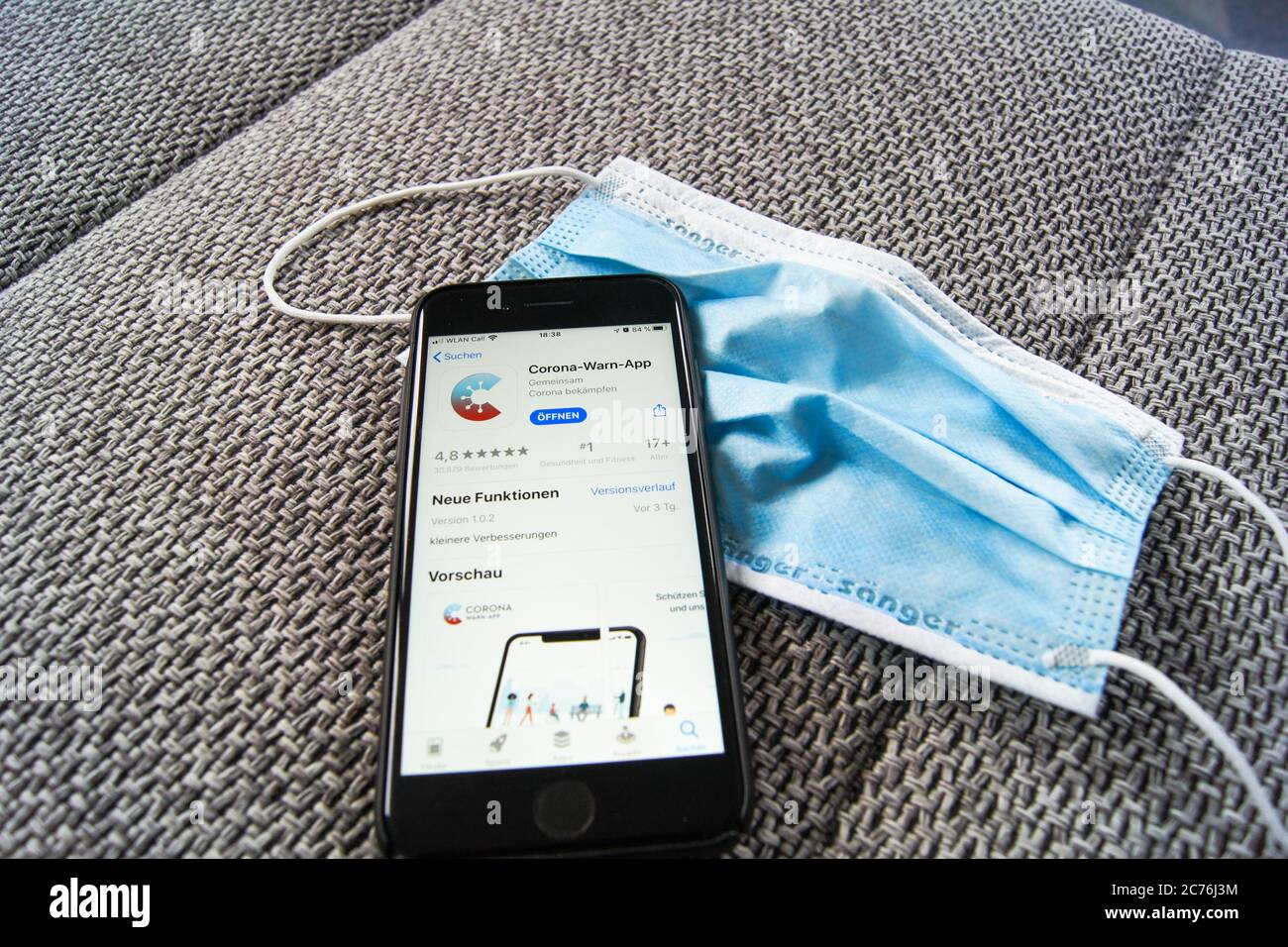 Corona Warn App du gouvernement fédéral allemand dans l'App Store d'Apple sur un smartphone portant un masque de protection. Banque D'Images