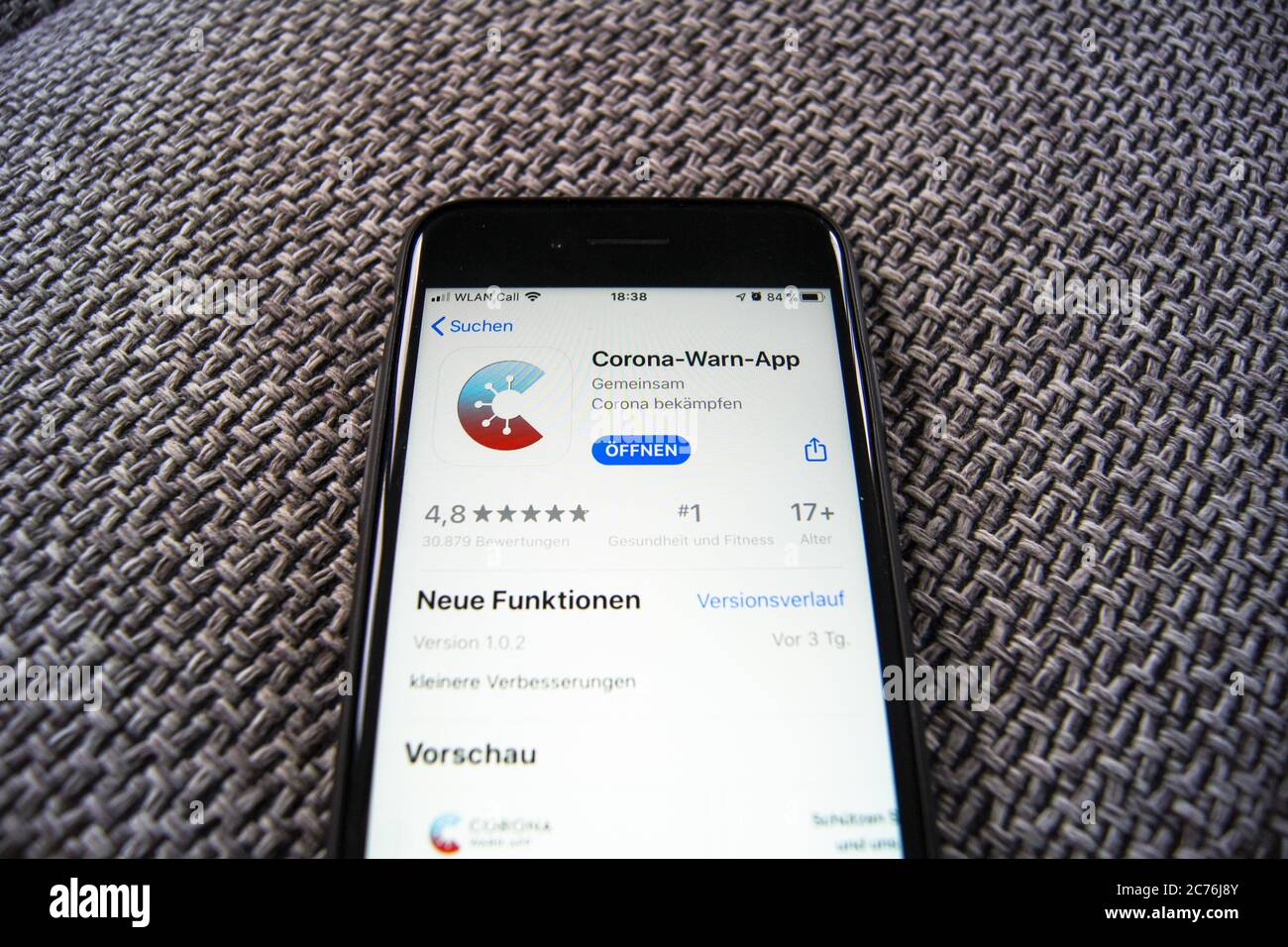 Corona Warn App du gouvernement fédéral allemand dans l'App Store d'Apple sur un smartphone en train d'aimer sur un fond textile. Banque D'Images