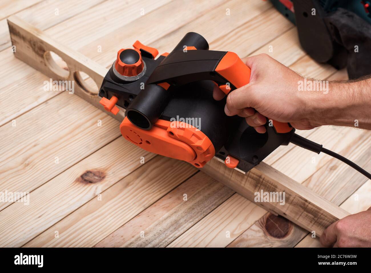 Rabot électrique à main mâle. Traitement de la pièce sur table en bois brun  clair Photo Stock - Alamy