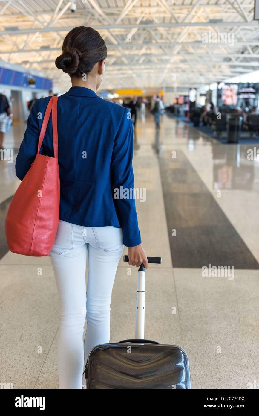 Une femme qui passe par le terminal de l'aéroport va à la porte d'embarquement  porte-monnaie et bagages à main pour les voyages en avion Photo Stock -  Alamy