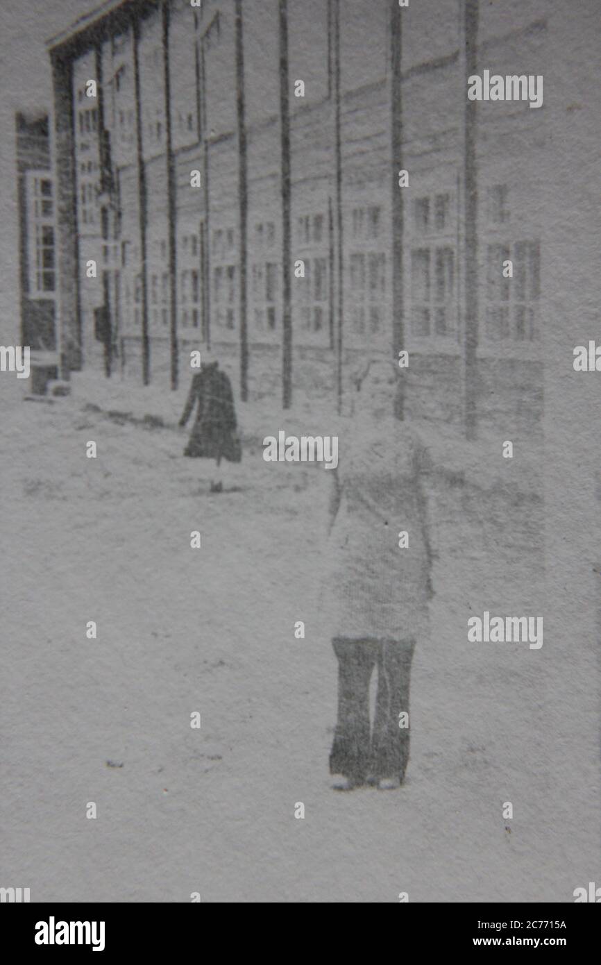 Fin années 70 vintage noir et blanc de style de vie photographie d'une femme debout devant un bâtiment institutionnel. Banque D'Images