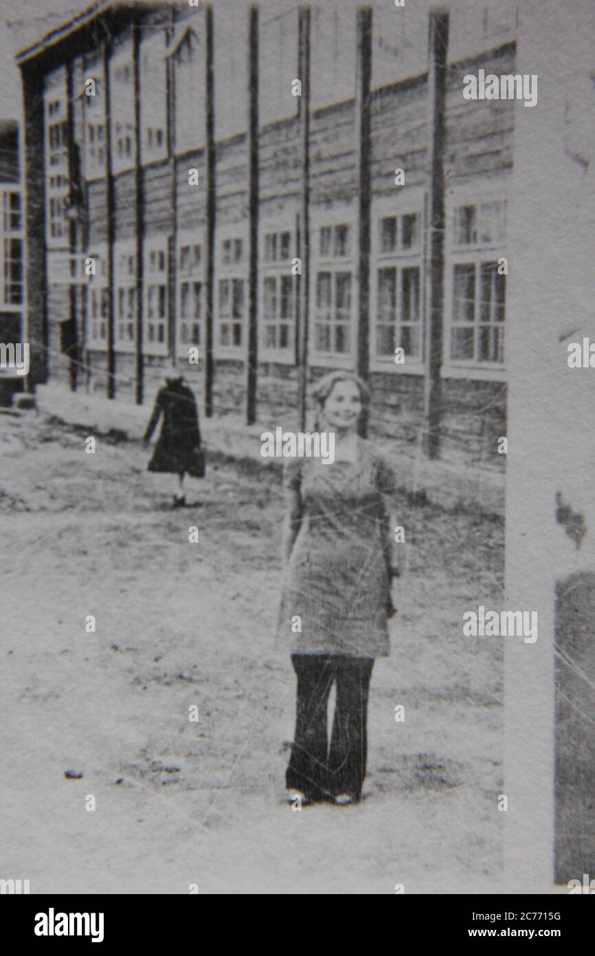 Fin années 70 vintage noir et blanc de style de vie photographie d'une femme debout devant un bâtiment institutionnel. Banque D'Images