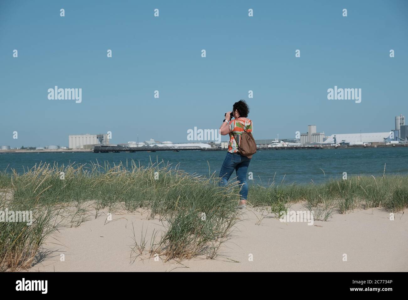 Vue arrière d'une femme debout sur la plage prenant une photo, France Banque D'Images