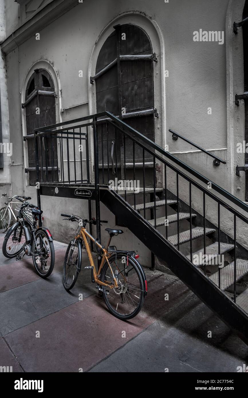 Vieux vélos garés sur des escaliers en fer sous le bâtiment historique avec portes massives verrouillées dans la ville intérieure de Vienne en Autriche Banque D'Images