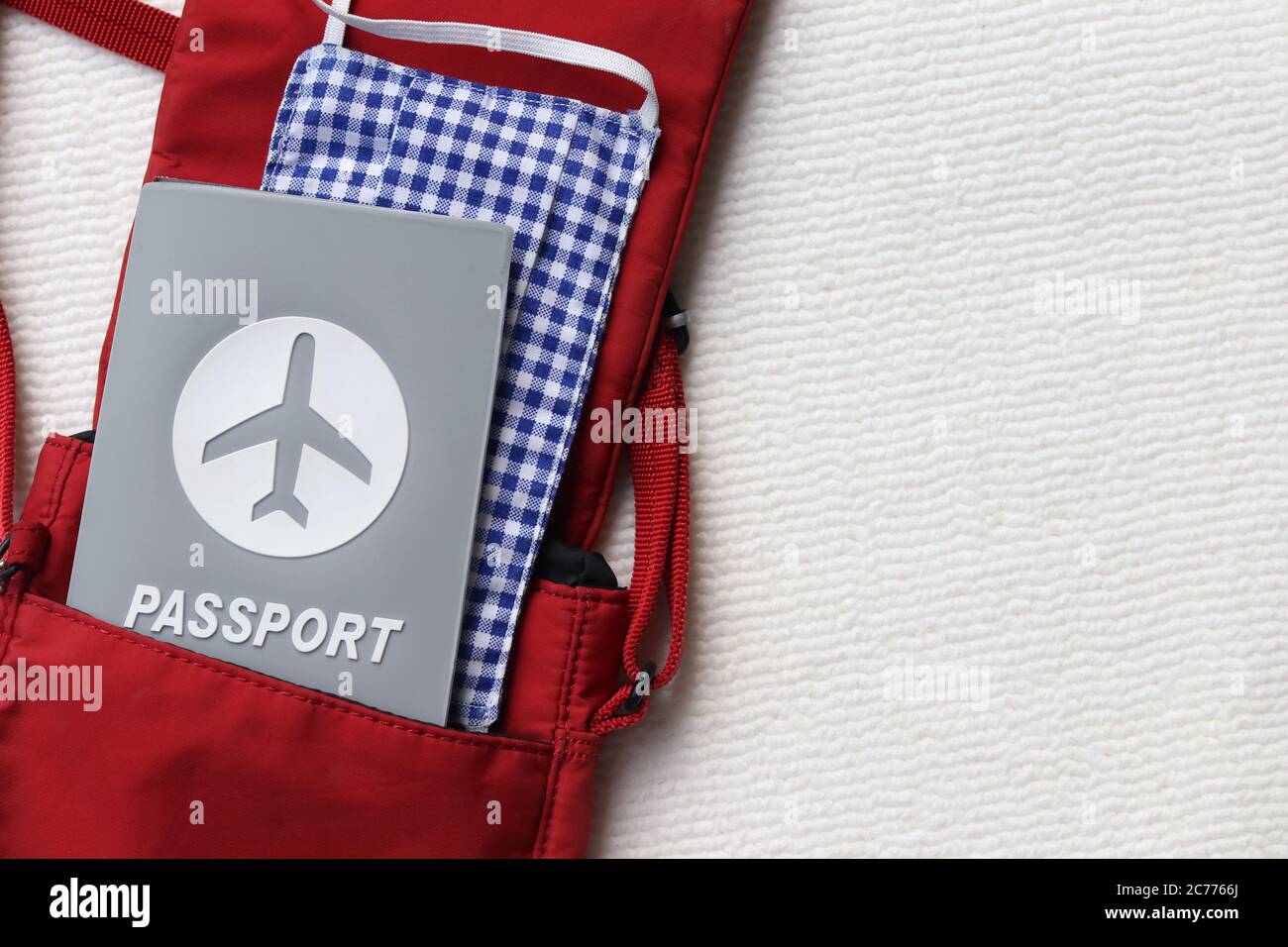 Passeport et masque en tissu dans un sac rouge à bandoulière avec espace pour copier sur fond blanc. Le tourisme et le voyage dans la nouvelle normale après la pandémie Covid-19. Banque D'Images