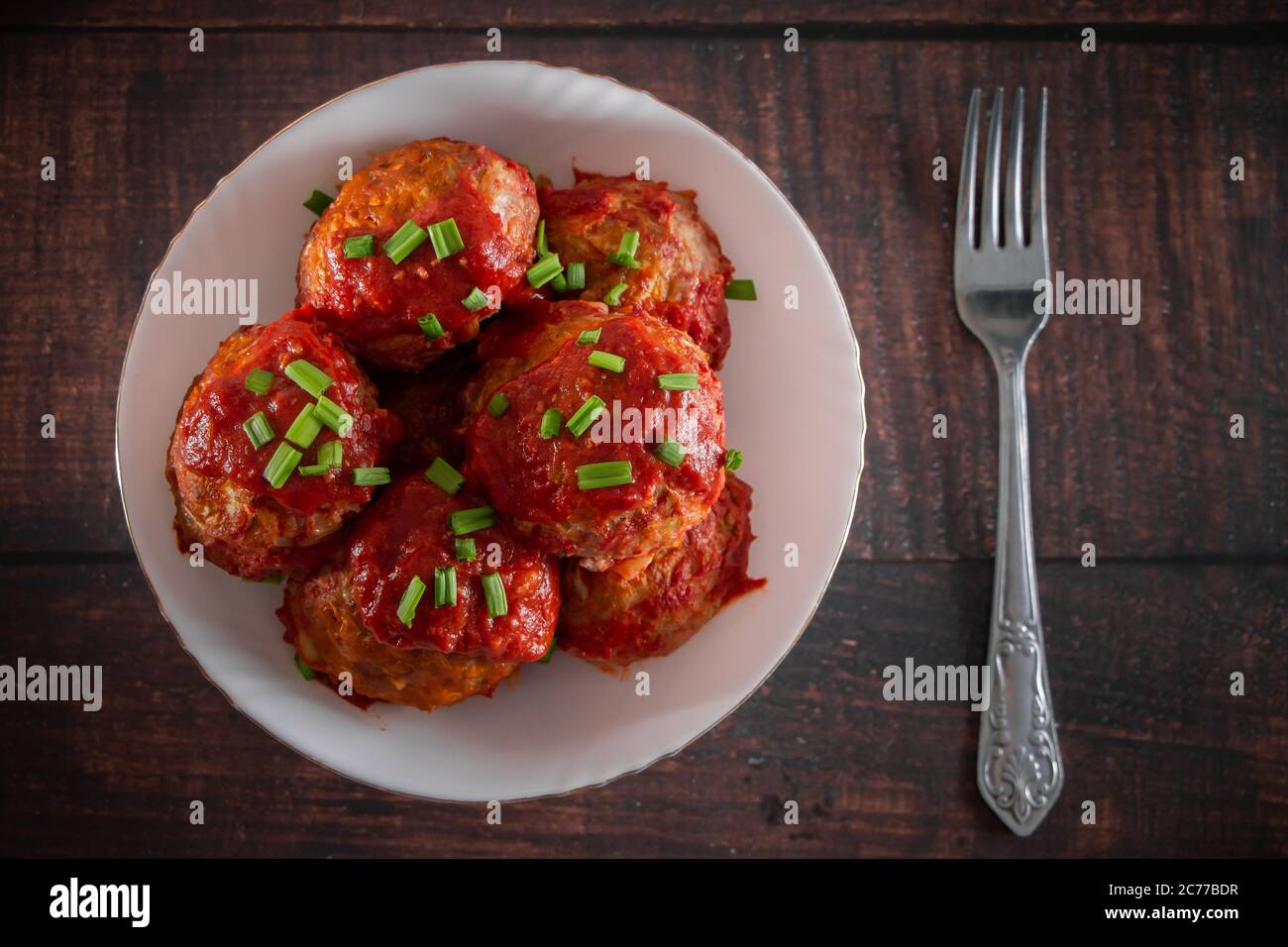 Boulettes de viande avec sauce tomate et herbes. Assiette avec boules de viande et fourchette sur fond sombre. Source de protéines pour la nutrition Banque D'Images