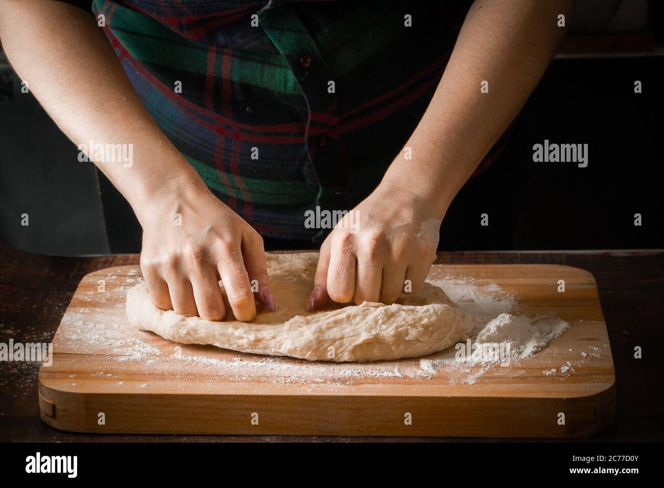 Gros plan des mains du cuisinier. Une femme prépare de la pâte à pétrir sur une planche à farine Banque D'Images