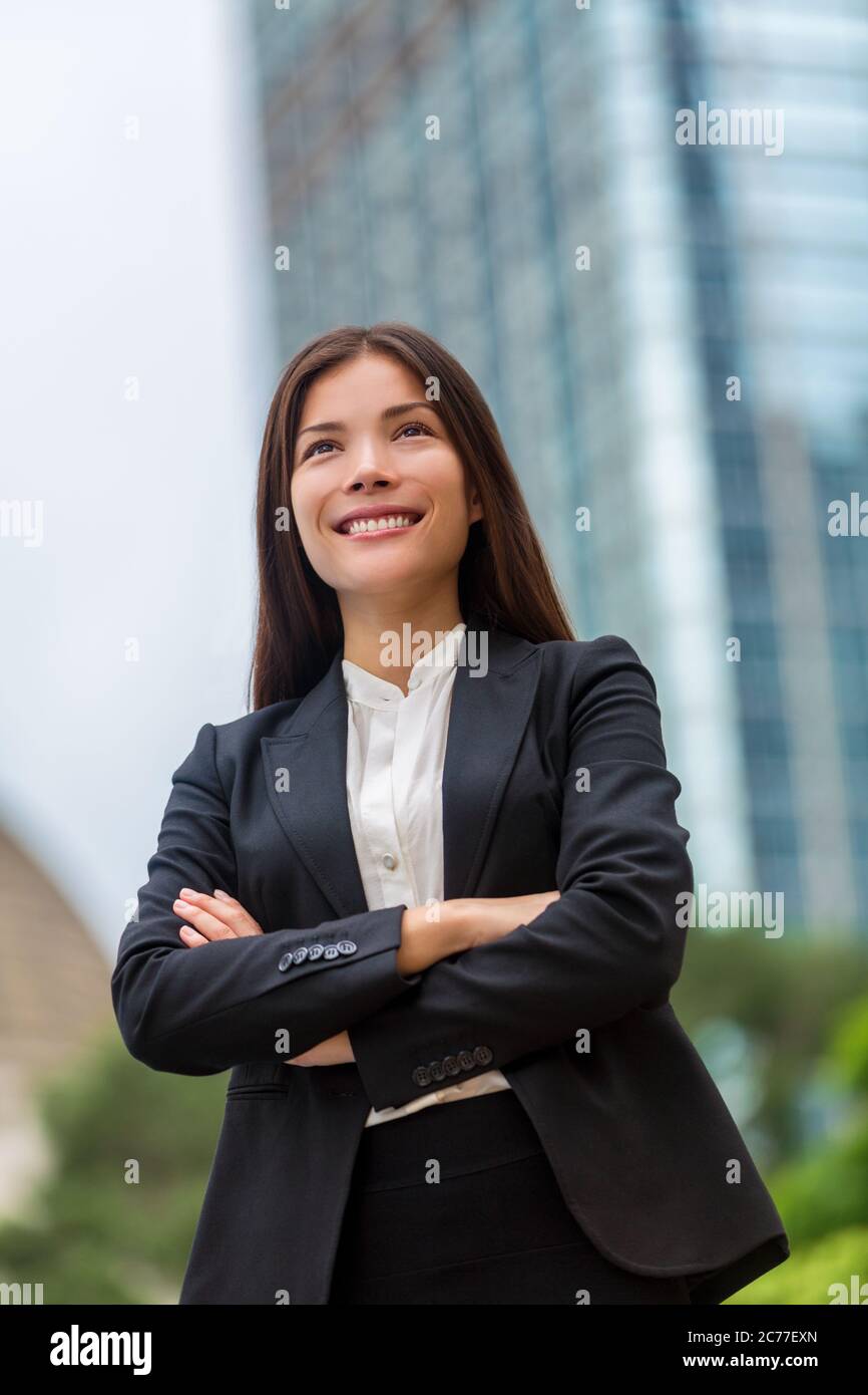 Femme d'affaires asiatique confiante à Hong Kong. Femme d'affaires debout à l'extérieur avec fond urbain de ville en costume armé. Jeunes Chinois multiraciaux Banque D'Images