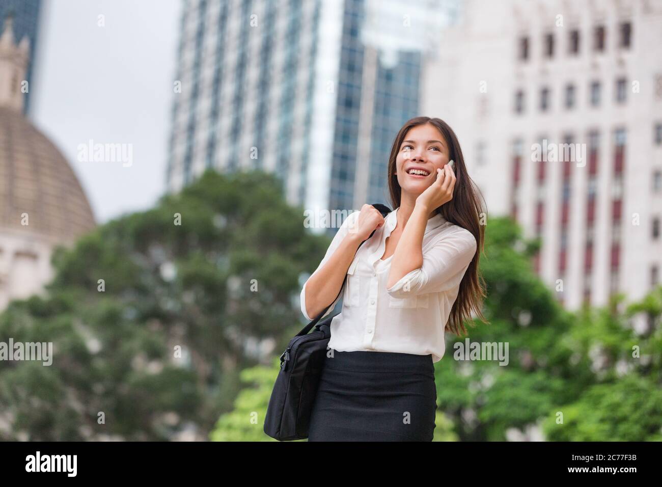 Femme d'affaires asiatique parlant au téléphone à pied se rendre au bureau de Hong Kong. Jeune femme d'affaires sur smartphone heureux. Chinois multiracial Banque D'Images