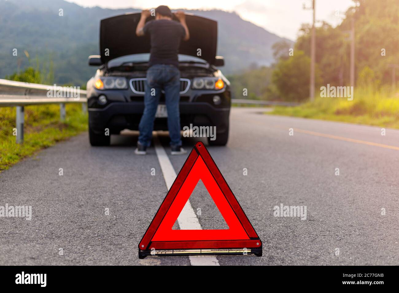 Triangle rouge sur la route pour l'avertissement ont la voiture avec la panne capot de voiture ouvert et homme fixant une voiture. Banque D'Images