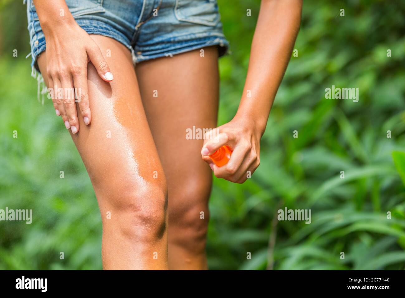 Spray anti-moustiques. Femme pulvérisant un insectifuge contre le virus zika punaises virus piqûres de virus sur les jambes peau à l'extérieur dans la forêt naturelle à l'aide d'une bouteille vaporisée Banque D'Images