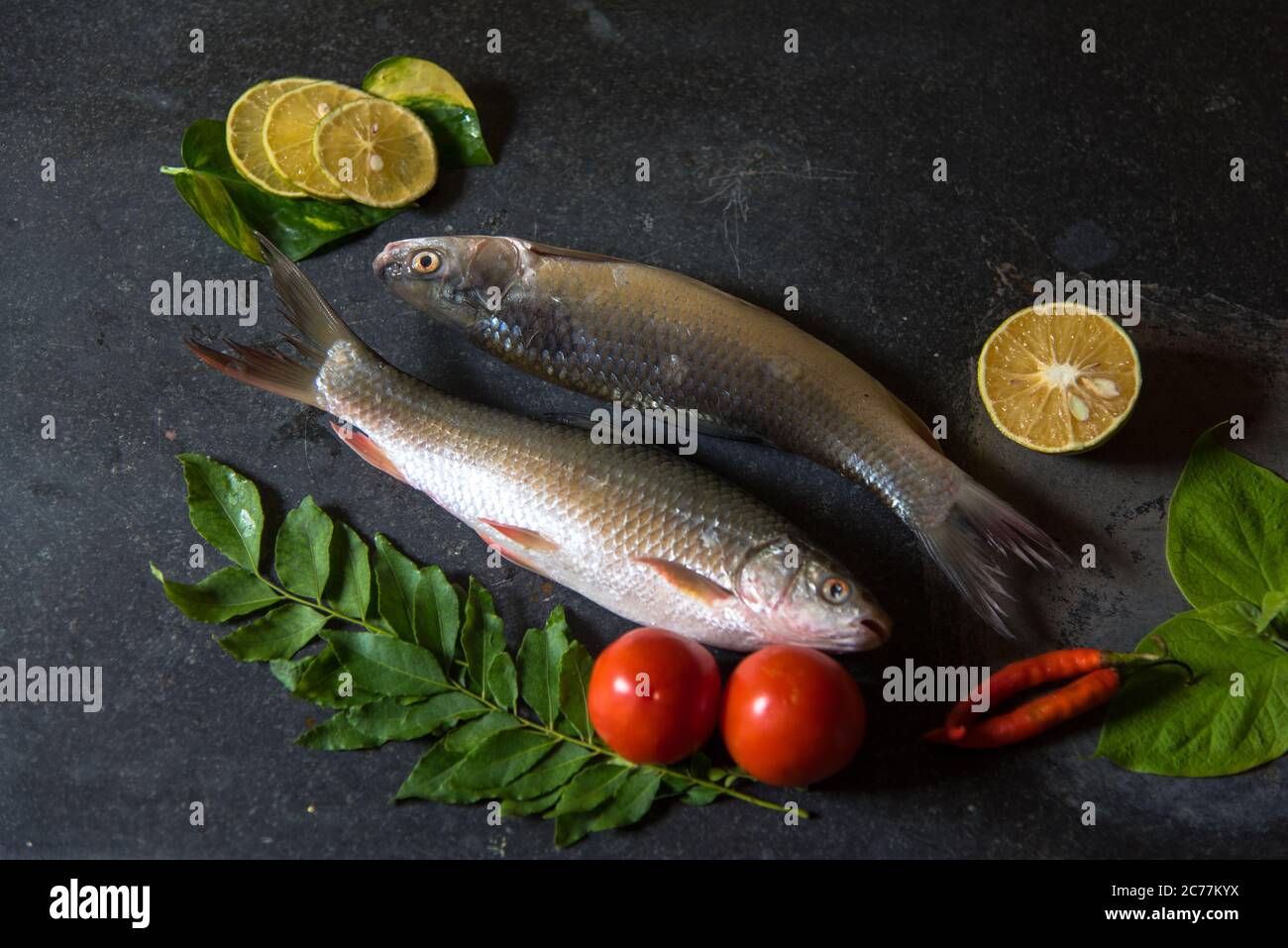 Poisson non cuit sur fond noir avec utilisation de l'accent sélectif sur une partie particulière du poisson et le reste du poisson et d'autres ingrédients flous. Banque D'Images