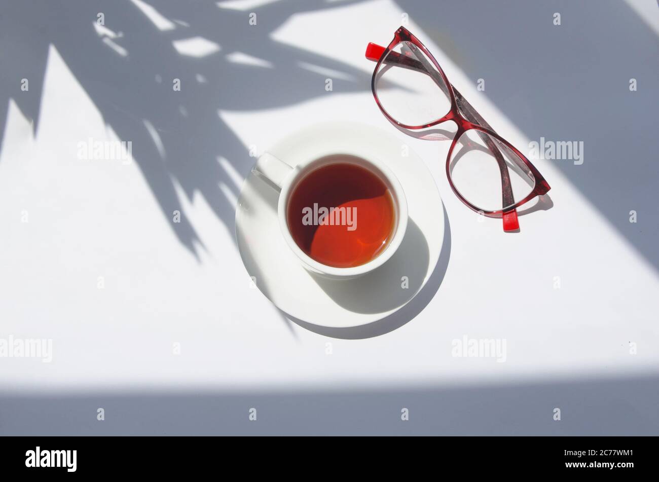 Tasse de thé blanc avec ombre au palmier et verres Banque D'Images
