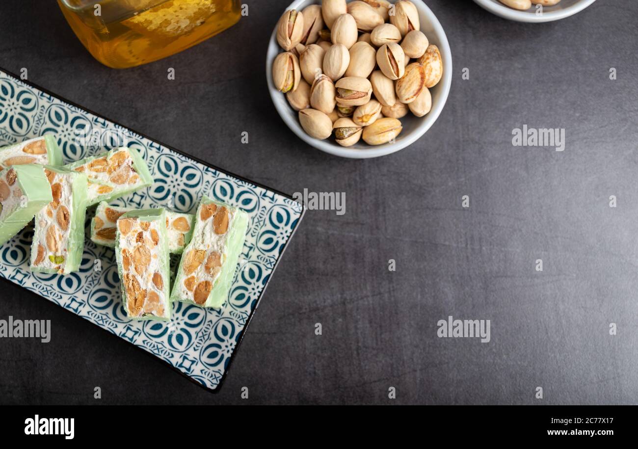 Nougat bio faites avec du miel, pistache, noisette, noix et amandes, sur un fond sombre. rustique Banque D'Images